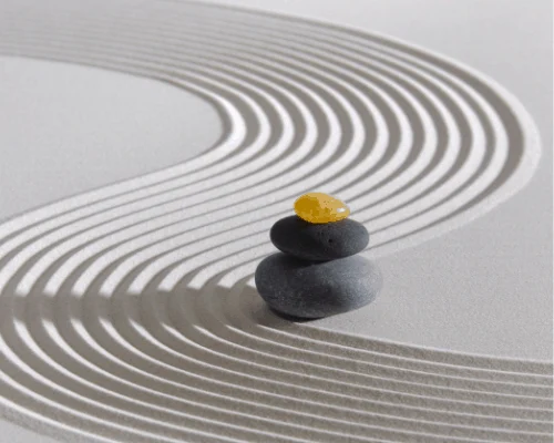 Galets empilés sur sable avec motifs ondulés, accent sur la sérénité et le zen