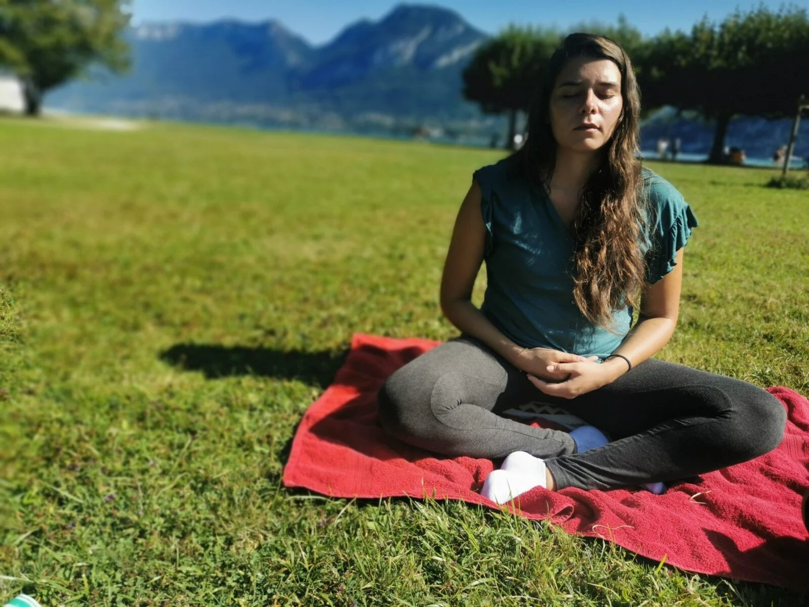 Femme méditant en plein air sur une couverture rouge dans un parc verdoyant