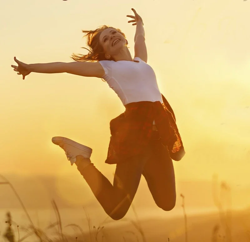 Femme sautant joyeusement au coucher du soleil sur un champ