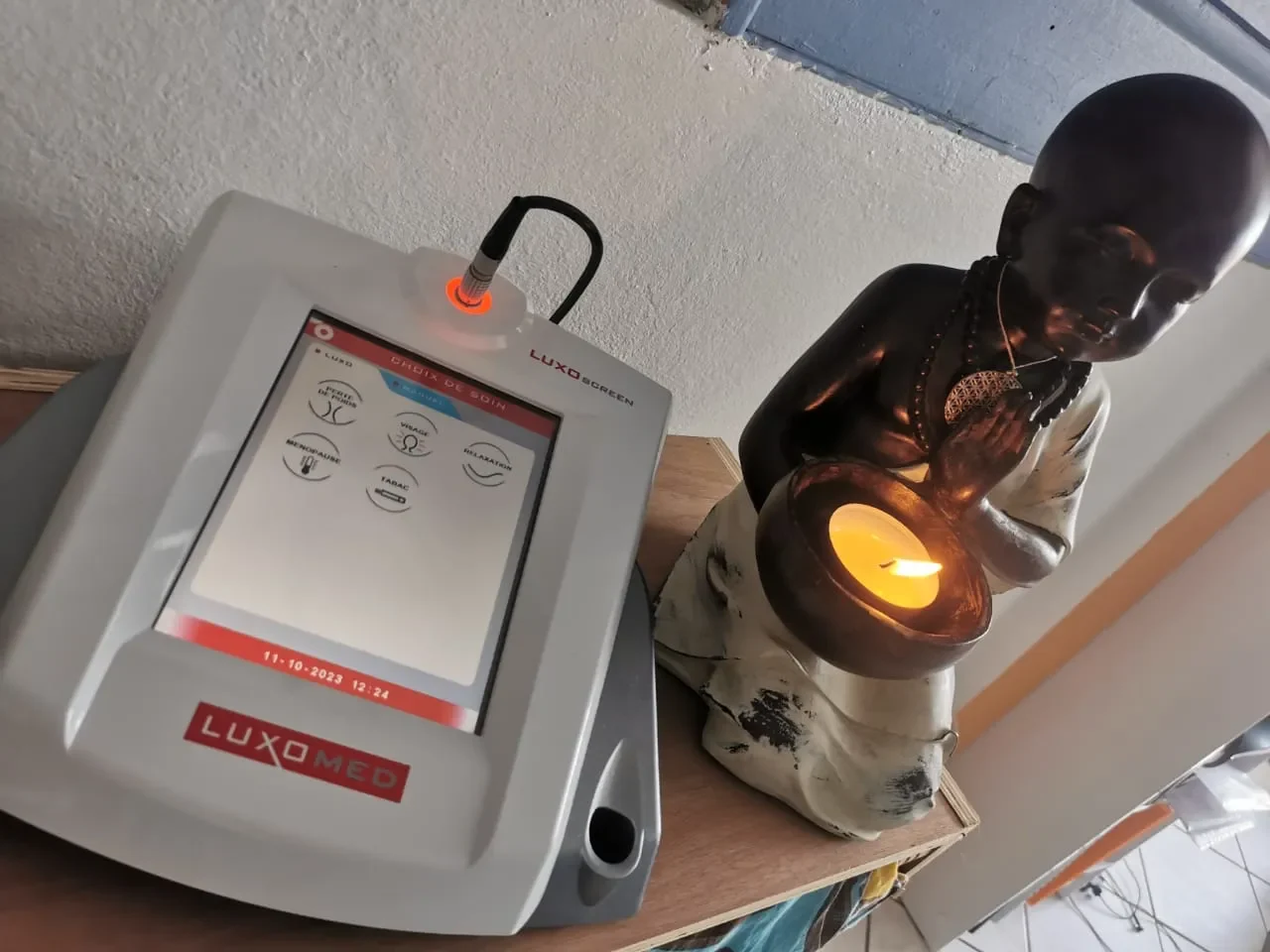 Appareil Luxoponcture et statue méditante avec bougie allumée