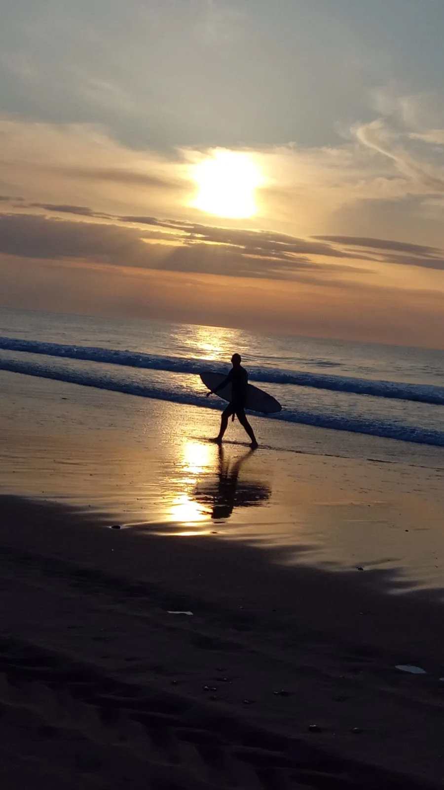 Surfeur marchant au coucher du soleil sur une plage paisible dans les Landes