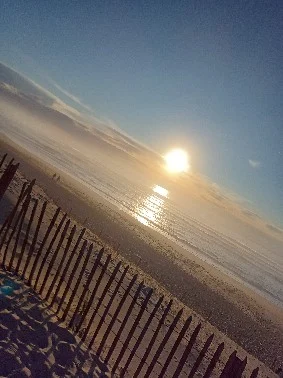 Coucher de soleil sur une plage avec clôture en bois.